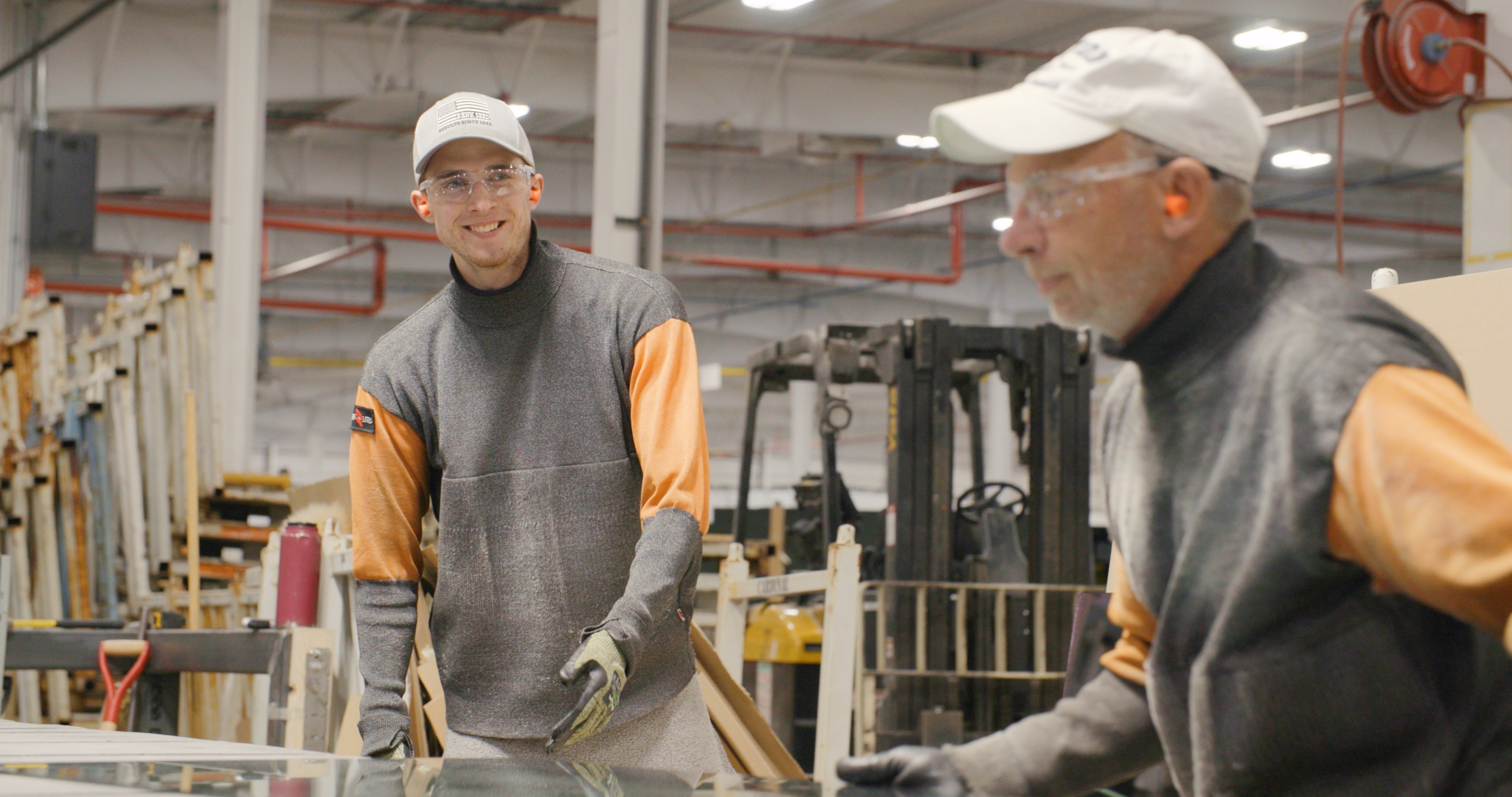 Two Cardinal SGCG Employees Moving Glass Together Smiling